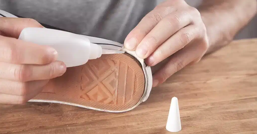 A view of a person putting super glue under the rubber shoe sole