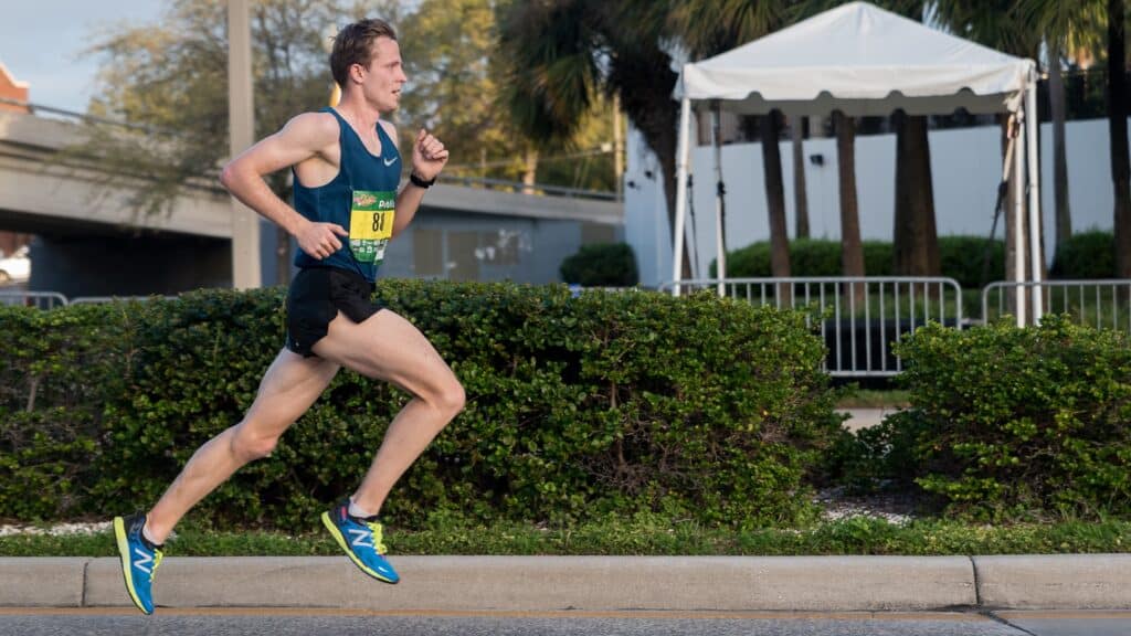 A view of an athlete running outdoors wearing blue new balance shoes